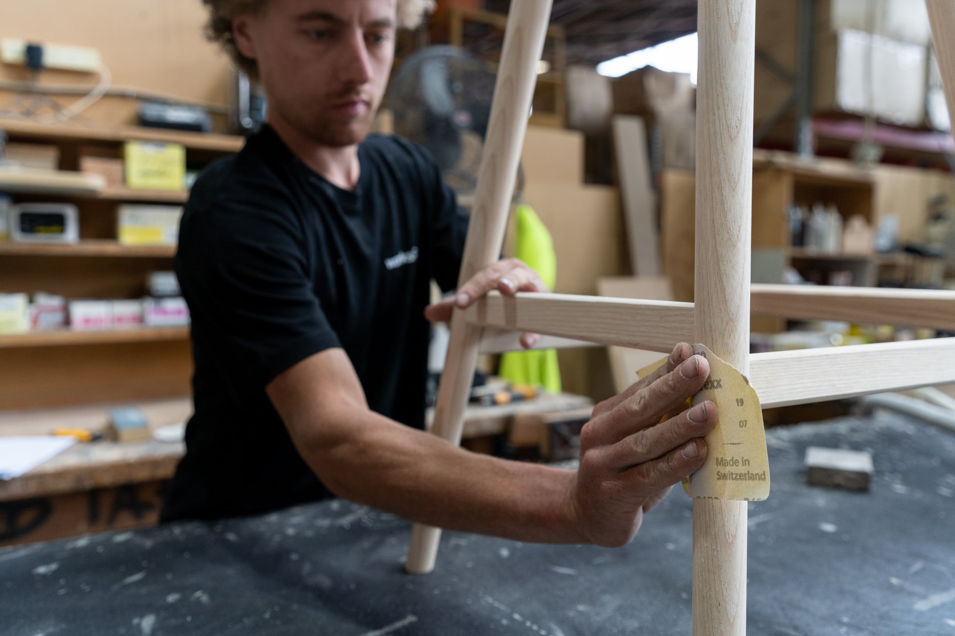 TH Brown craftsman hand-sanding a timber furniture frame in the Adelaide workshop, reflecting the care behind Australian-made craftsmanship.
