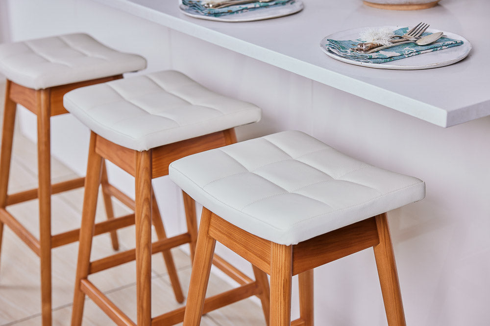 TH Brown Martelle Bar Stools with warm timber frames and white upholstered seats, styled for relaxed entertaining in a bright modern kitchen.