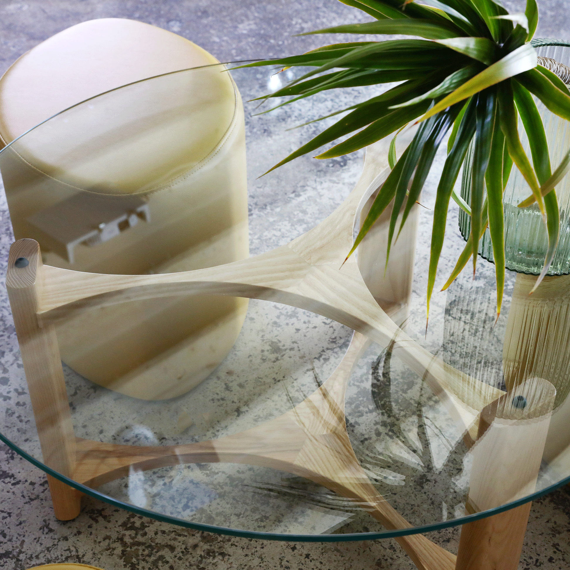 TH Brown Rondo Coffee Table with sculptural timber frame and glass top, styled with greenery in a relaxed, light-filled contemporary interior.