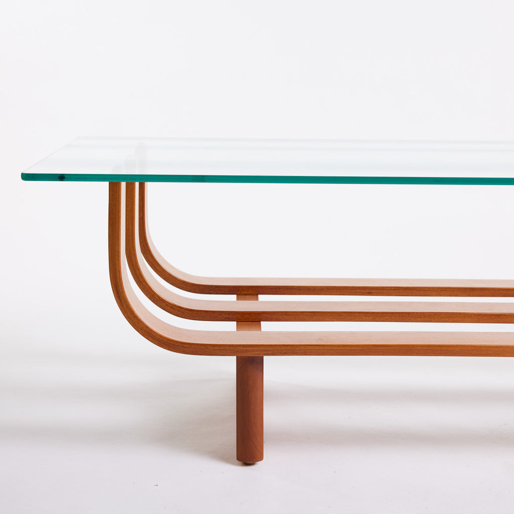 TH Brown Aquarius Coffee Table in Teak Ash with clear glass, blending natural timber warmth and sculptural form for timeless modern Australian living.